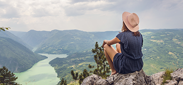 Woman looking out into valley from top of mountain
